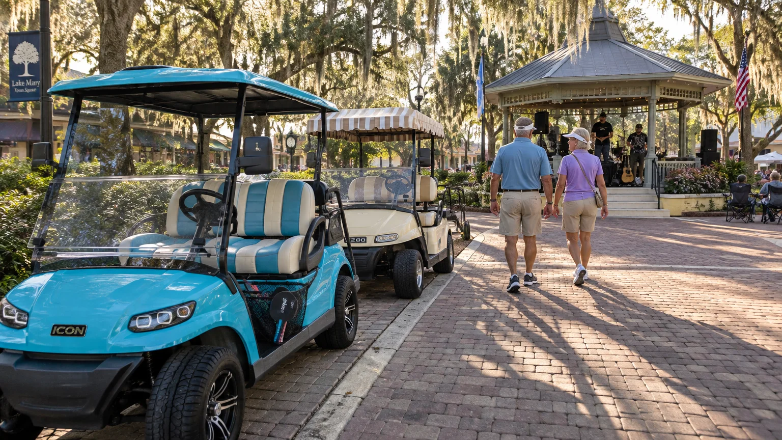 Golf carts parked on a brick path as an older couple walks toward an outdoor gazebo with live musicians.